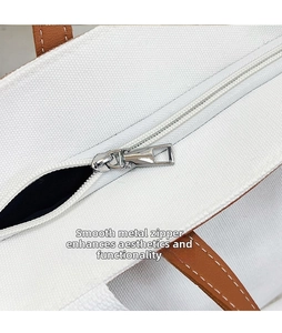 Close-up of smooth silver metal zipper head on large canvas tote bag with leather strap
