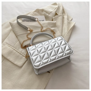 Detail of silver metallic quilted bag with woven handle and chain strap on blazer