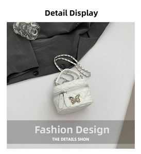 Detail shot of white quilted mini box bag with silver butterfly and chain strap