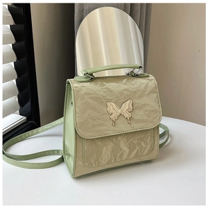 Detail of a pleated PU leather bag with a silver butterfly buckle and bicolor finish