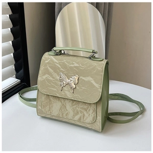 Detailed close-up of light green crossbody bag with golden butterfly clasp and texture