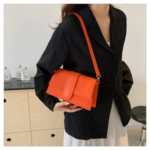 Detail of orange woven leather texture on a stylish shoulder bag worn by a model