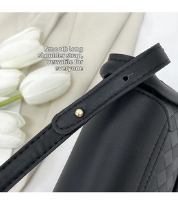 Detail of adjustable black leather strap with gold buckle and quilted texture on crossbody bag