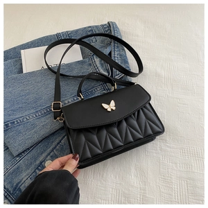 Detail der schwarzen Stepptasche mit weißem 3D-Schmetterling und goldenen Beschlägen