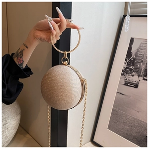 Detail of spherical evening bag featuring golden glitter finish and rhinestone handle