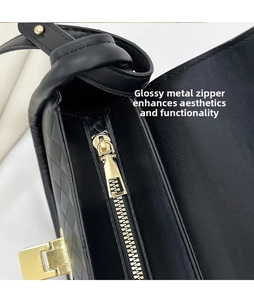 Detail of golden polished zipper and checkered embossed texture on black handbag