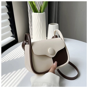 Detailed view of a vintage two-tone leather crossbody bag with rounded flap and strap
