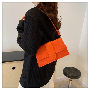 Fashionable bright orange baguette bag featuring a unique geometric embossed texture