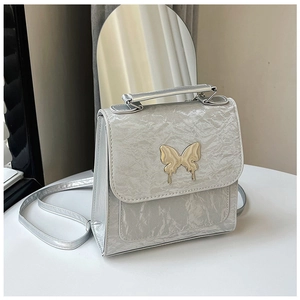 Close-up of silver wrinkled texture handbag with a golden liquid metal butterfly clasp