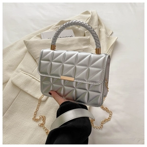 Close-up of silver quilted handbag with golden chain strap and woven top handle