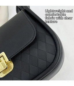 Close-up of black quilted faux leather handbag with square gold rotating metal lock