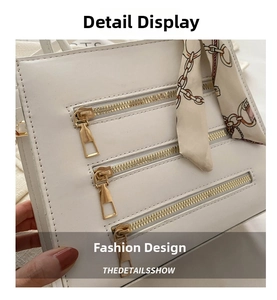 Detail of white faux leather handbag featuring triple gold zippers and silk scarf handle