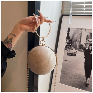 Close-up of champagne gold spherical evening bag with rhinestone ring handle and chain