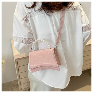 Detail of pink embossed leather handbag with pearl handle and curved hourglass base