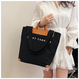 Detail of canvas tote bag with brown leather accents and long shoulder straps