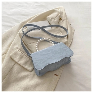 Detail of light blue pleated PU handbag with pearl handle and wavy edge design