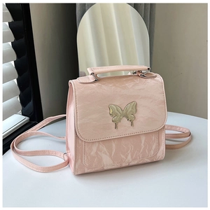 Detail of pink PU backpack with gold butterfly buckle and marble texture on a white table