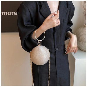 Detail of glitter spherical evening bag with diamond-encrusted handle and gold chain