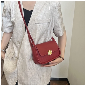 Detail of red crossbody bag with golden buckle and quilted texture on side panels