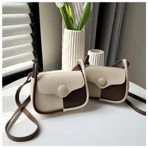 Detail view of two vintage saddle bags in beige and brown faux leather on a desk