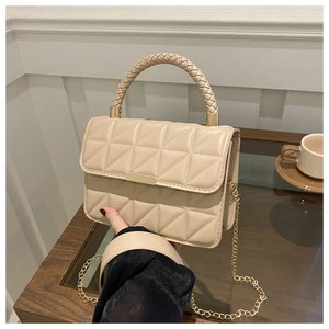 Detail of beige quilted handbag with gold hardware and woven handle texture