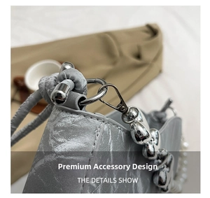 Macro detail of grey textured shoulder bag featuring silver heart and pearl chain hardware