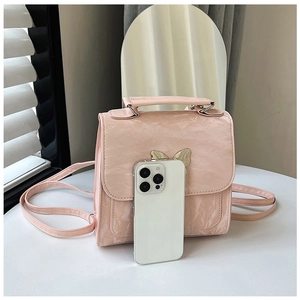 Pink pleated mini backpack next to a smartphone showing its compact travel size