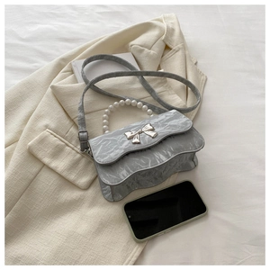 Detailed view of grey pleated texture bag with silver bow and pearl handle