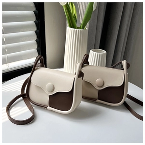 Detail shot of two-tone contrast flap bags with round buckles in warm natural sunlight