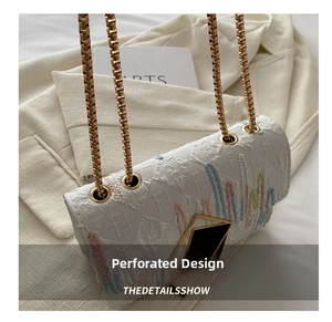 Detail der perforierten weißen Handtasche mit farbiger Stickerei und goldener Kette
