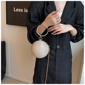 Detail of champagne gold sphere evening bag featuring a metal ring handle and chain
