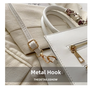 Detail of white leather bag with gold hooks, zipper and floral scarf wrapped on handle