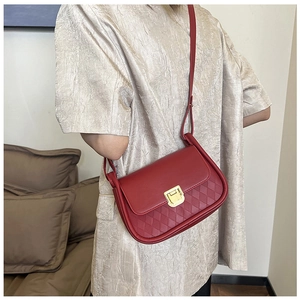 Detail of red leather crossbody bag with gold square buckle and woven texture detail