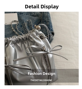 Detail of silver drawstring bucket bag with metal zippers and decorative bow elements