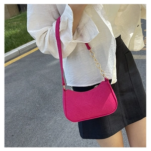 Close-up of hot pink crescent shoulder bag with fabric texture and gold chain strap