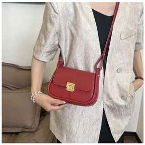 Close-up of red crossbody bag featuring diamond quilted texture and golden square lock