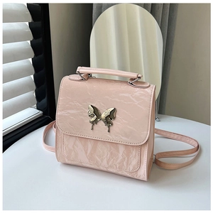 Close-up of pink crinkled patent leather handbag with golden butterfly metal ornament