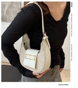 Detailed view of woven beige half-moon bag featuring white leather trim and gold buckle