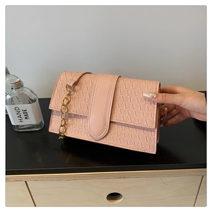 Detailed view of pink geometric embossed handbag with stylish decorative gold chain