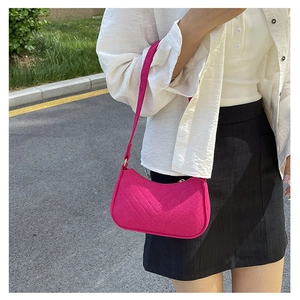 Detail of magenta quilted underarm bag featuring symmetrical V-stitch texture and strap