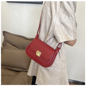 Detail of red crossbody bag featuring quilted texture and a gold-tone square lock