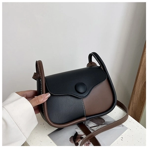 Close-up of retro black and brown leather crossbody bag with stitching and large button