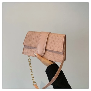 Detail of pink flap handbag featuring geometric triangle embossed texture and gold chain