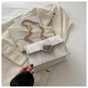 Detail der weißen strukturierten Stofftasche mit bunter Stickerei und Goldkette