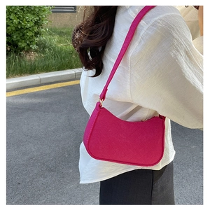 Close-up of a magenta vintage shoulder bag with fabric texture and gold hardware on a model