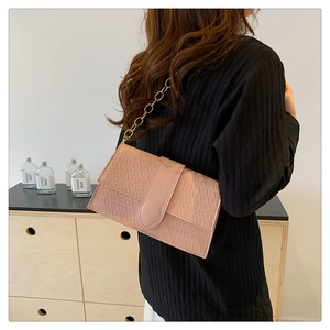 Detail of pink shoulder bag featuring geometric embossed texture and gold chain strap