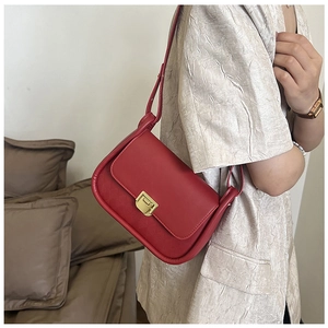 Close-up of red crossbody bag with geometric diamond pattern and gold square buckle