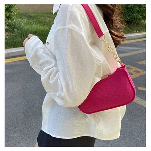 Close-up of rose red quilted shoulder bag with golden chain and V-pattern stitching