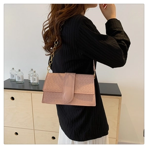 Detail of pink shoulder bag featuring geometric triangle embossing and gold chain strap