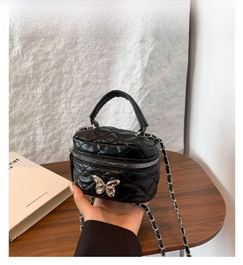 Detail of black quilted leather box bag with silver butterfly clasp and chain strap